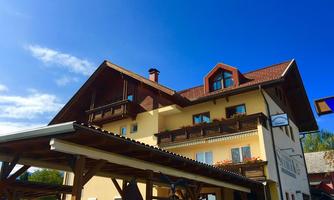A charming house in alpine style with a large overhang. The sky is clear and blue, creating an inviting atmosphere.