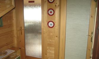 A warm wooden paneling with a glass door and two additional doors. Next to it, three round pictures are hanging.