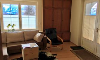 A bright living space with a comfortable sofa and a chair. Large windows let in plenty of light and showcase a beautiful view.