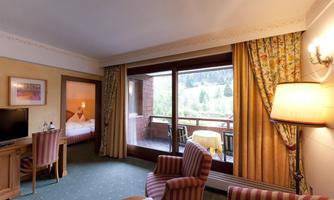 A cozy hotel room with a view of the mountains. The room is equipped with a table, chairs, and a television.