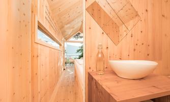A modern wood interior environment with a clear view outside. On the table is a glass bottle and a white bowl.