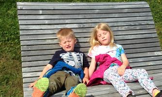 Two children are lying relaxed on an attractive meadow. They are enjoying the sun and the fresh air.