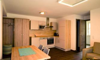 Modern kitchen with wood cabinets and a dining table. Bright rooms with a cozy atmosphere.
