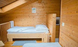 A cozy bedroom with wooden walls and two separate beds. The decor radiates warmth and a connection to nature.