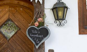 A heart-shaped sign with the inscription "Tälli's Holiday Home" hangs from a wooden beam. Next to it is an elegant lantern.