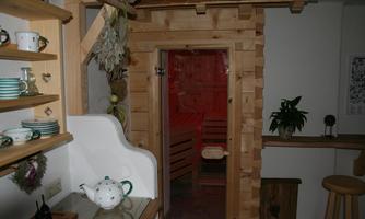 A cozy room with wooden sauna access. Next to the door are shelves and plants that create a relaxed atmosphere.