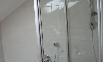 A modern bathroom with a bathtub and a shower cubicle. The walls are brightly tiled and there is plenty of daylight.