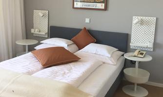 A stylishly furnished bedroom with a large double bed and comfortable pillows. On the walls, there are nightstands and artworks that give the room a personal touch.