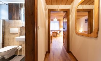 An inviting hallway with wooden walls and a beautiful floor. In the background, there is a bright living area with a window.
