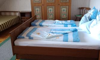 A cozy bedroom with a double bed and two single beds.  
There is a beautiful wardrobe with decorative doors on the wall.