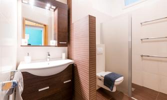 A modern bathroom with a sink and a large mirror. The shower is separated by a glass wall and there is a bright color scheme.