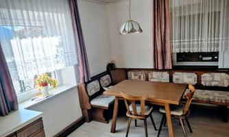 A cozy kitchen nook with a wooden table and chairs. Large windows bring a lot of daylight into the room.