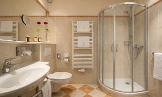 An elegant bathroom with a shower and a marble table. Fresh flowers and clean towels create an inviting atmosphere.