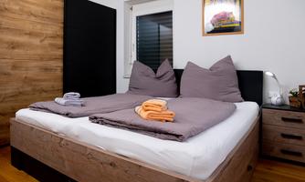 A cozy bedroom with a large bed and two pillows. Fresh towels in different colors are placed on the bed.