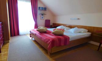 A cozy bedroom with a double bed and colorful pillows. Large windows let in plenty of light and create an inviting atmosphere.
