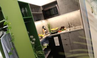 A modern kitchen with gray walls and a black cooking surface. Fresh ingredients and kitchen appliances are arranged on the countertop.