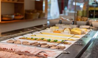 A rich buffet with various types of sausages and cheeses. Fresh herbs and ingredients complement the selection.
