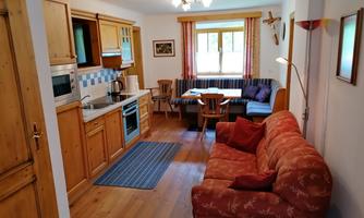 A cozy apartment with wooden furniture and a fully equipped kitchen. The dining area is bright and cheerful, perfect for shared meals.
