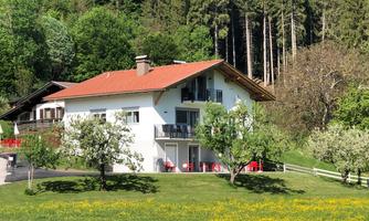 A beautiful house in a green landscape with trees and flowers. The surroundings appear calm and inviting.