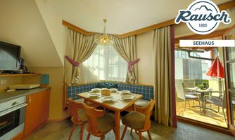A cozy kitchen with a dining table and chairs. Large windows provide plenty of light and access to a balcony.