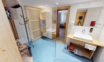 A modern bathroom with a glass shower and a minimalist decor. The walls are bright, and there are wood elements for a cozy atmosphere.