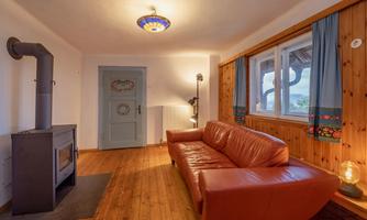 A cozy living room with a brown leather sofa and wooden floor. The room has a warm atmosphere and a fireplace.