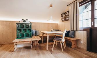 A cozy dining area with a wooden table and benches. A green cupboard stands against the wall and the light is warm and inviting.