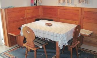 A cozy dining area with a wooden table and four chairs. The walls are made of wood and there is a lovely table decoration.