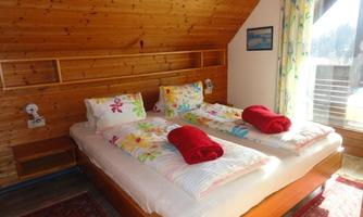 A cozy bedroom with two beds and colorful pillows. Large windows provide plenty of light and a pleasant atmosphere.