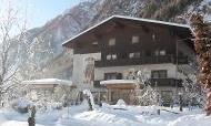A cozy building in winter, surrounded by snow and mountains. The trees are covered in snow, creating a serene winter landscape.