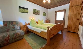 A cozy bedroom with two single beds and wood decor. The room has a bright atmosphere and a view of nature.