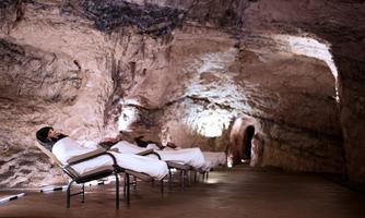 A relaxing room in a cave with comfortable loungers. People enjoy the calm atmosphere and the natural rock structure.