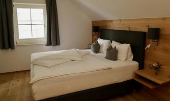 A modern bedroom with a comfortable double bed and two pillows. The walls are in a light shade, and the wood design creates a cozy atmosphere.