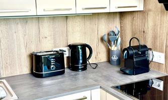 A modern kitchen with a concrete countertop. On the counter are a toaster, a kettle, and a Nespresso machine.