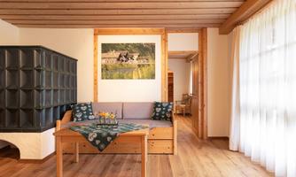 A cozy living space with wooden interior and a seating area. On the wall hangs a picture of a rural landscape.