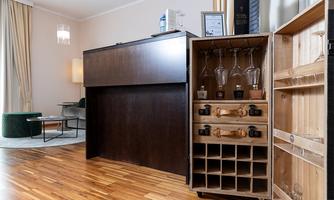 A modern bar with glasses and bottles in a stylish room. The wooden floor and soft lighting create an inviting atmosphere.
