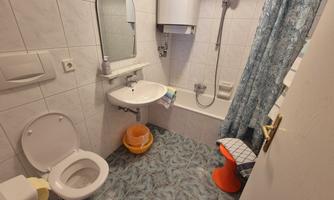 A small bathroom with a bathtub and a shower. There is a toilet and a sink, as well as some color and accessory elements.