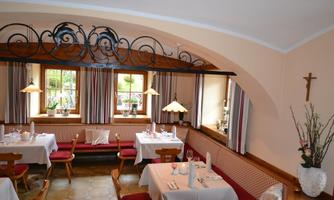 A cozy restaurant with beautifully set tables. The windows are decorated with curtains and there is warm lighting.