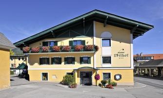 A picturesque building in alpine style with a yellow facade and colorful flowers. It is located in a quiet setting and offers an inviting atmosphere.