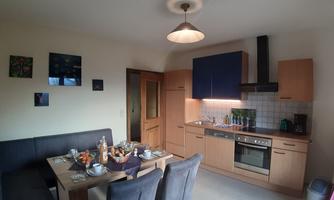 A modern kitchen with a dining area. The kitchen is well equipped with a refrigerator with freezer compartment, dishwasher, ceramic hob, oven, filter coffee machine, kettle, egg cooker, and toaster.