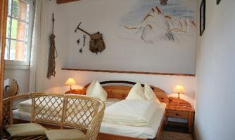 A cozy bedroom with wooden formations and friendly light. On the wall, there is a picturesque mountain landscape.
