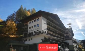 A modern building with several floors and large windows. On the left side, a sign for the garage is visible.