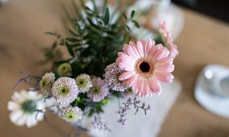 A beautiful bouquet with a pink gerbera and various other flowers. The bouquet is on a wooden table.
