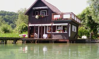 A charming turnkey wooden house by the water with a small balcony. Surrounded by lush nature and a tranquil body of water.