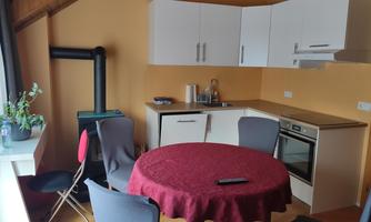 A modern kitchen with a round table and chairs. The walls are painted in a warm yellow tone.