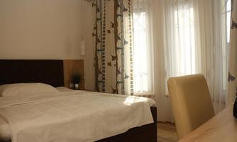 A cozy bedroom with a double bed and a desk. Large windows let in plenty of daylight and create a bright atmosphere.
