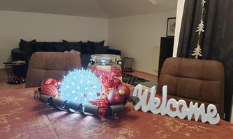 A festively decorated table with a bright Christmas centerpiece and a "Welcome" sign. In the background, cozy seating areas can be seen.