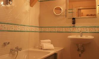 A modern bathroom with a bathtub, a sink, and wooden flooring. Walls in soft colors with a floral border.