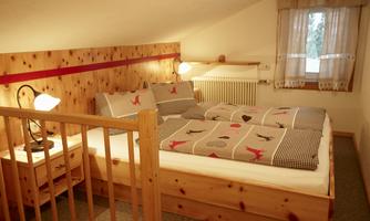 A cozy bedroom with a double bed and wooden paneling. The window provides daylight and an inviting atmosphere.