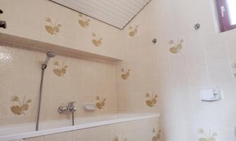 A bathroom with a bathtub and bright, blooming wallpaper. The walls are decorated with floral patterns and there is a shower.